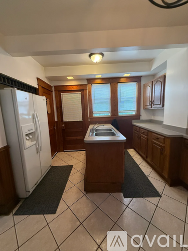 A kitchen with a refrigerator, sink, and cabinets.
