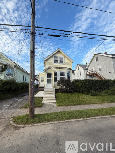 A house with a front yard and a telephone pole in front of it.