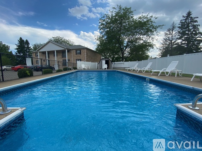 A large swimming pool with a house and trees in the background.