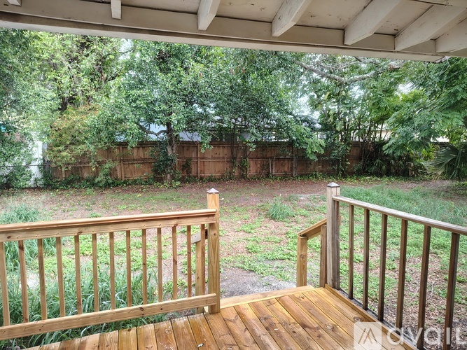 A wooden deck with a railing overlooks a grassy area.