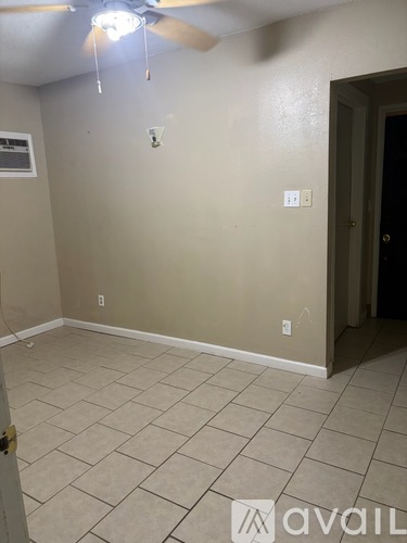 A room with a ceiling fan and tile flooring.