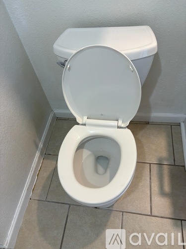 A white toilet with the seat up in a small bathroom.