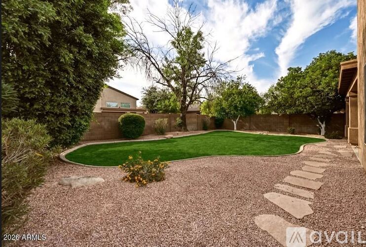 A backyard with a gravel path and a green lawn.