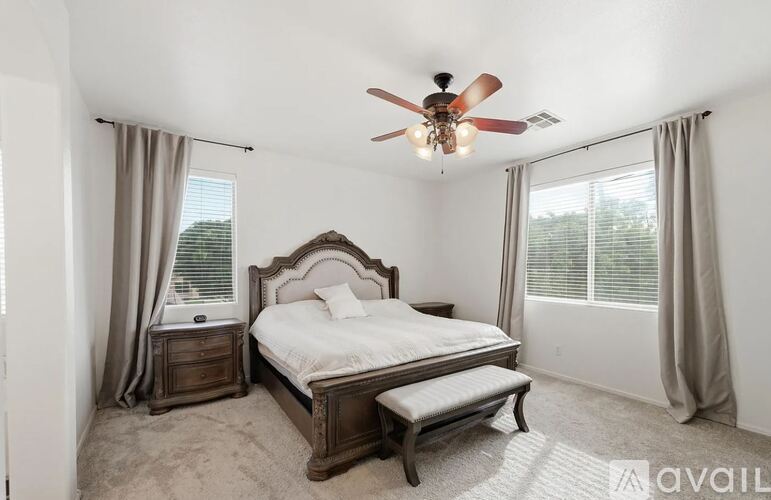 A bedroom with a bed, nightstand, and window with curtains.