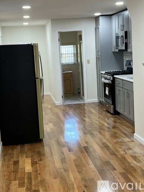 A kitchen with a black fridge and wooden floors.