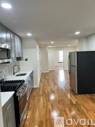 A kitchen with wooden floors and a black refrigerator.