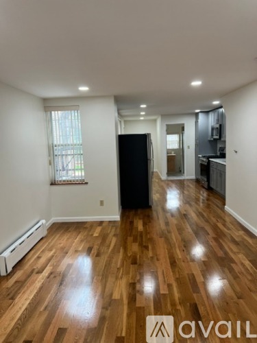A room with wooden floors and a black refrigerator.