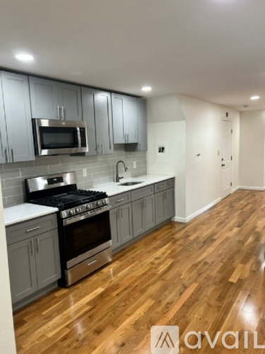 A kitchen with wooden floors and grey cabinets.
