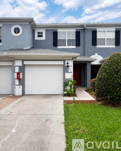 A grey house with a red door and a white garage door.