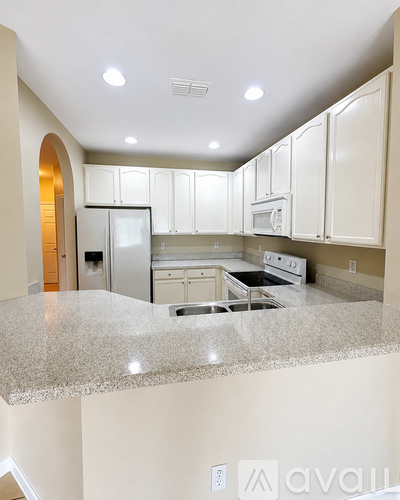 A kitchen with granite countertops and white cabinets.