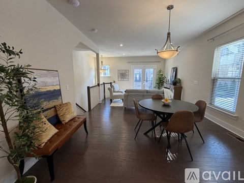 A living room with a brown bench and a round table with chairs.