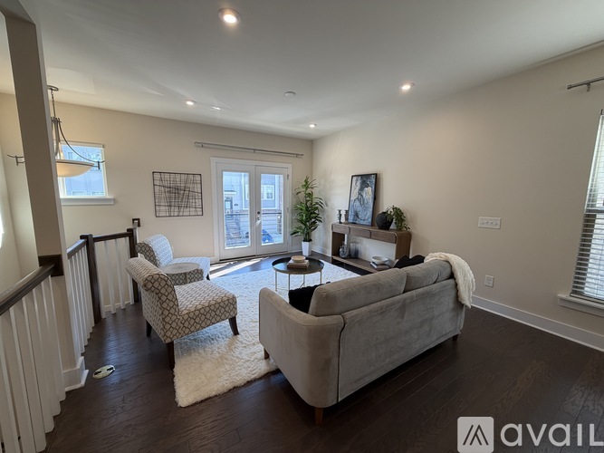 A living room with a couch, chairs, and a rug.