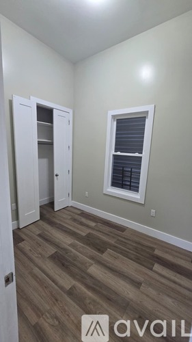 A room with a wooden floor and a window with blinds.