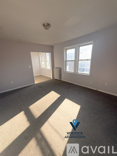 A spacious room with a carpeted floor and two windows letting in natural light.