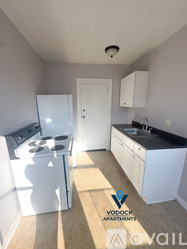A Vodock Apartments kitchen with white appliances and cabinets.