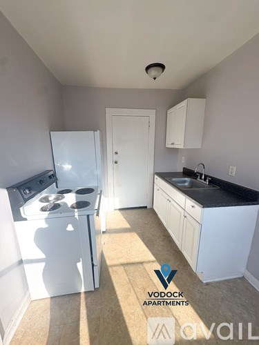 A Vodock Apartments kitchen with white appliances and cabinets.