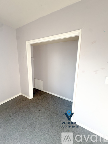 A room with a carpeted floor and a doorway leading to another room.