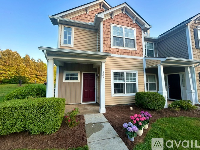 A two-story house with a red door and a front yard with a walkway and flower pots.