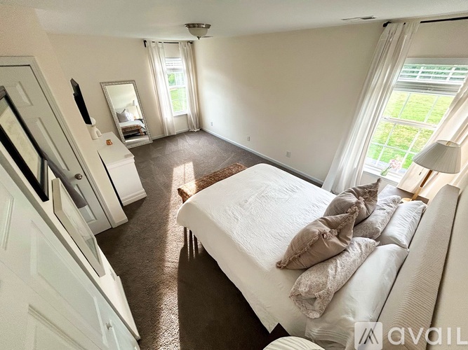 A bedroom with a large bed and a window with curtains.