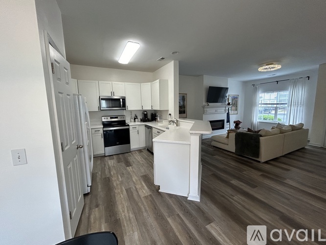 A kitchen with white cabinets and a wooden floor.