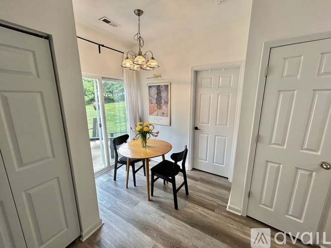 A dining room with a table set for two and a chandelier hanging from the ceiling.