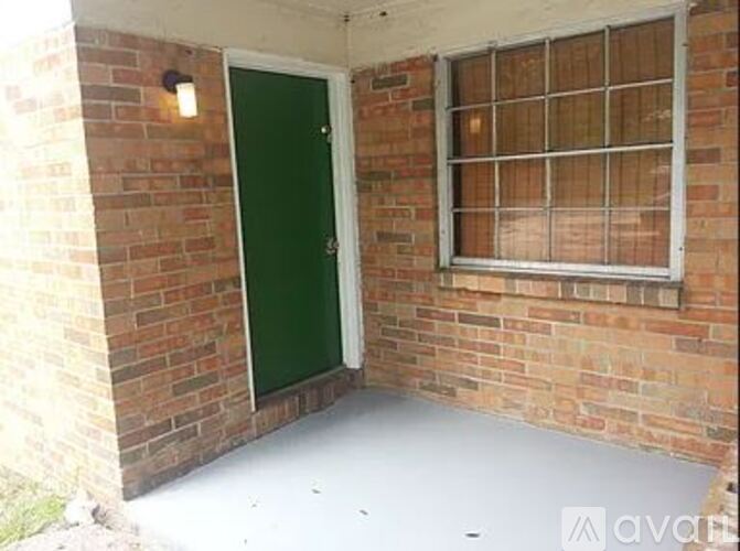 A green door is on the left side of a brick wall.
