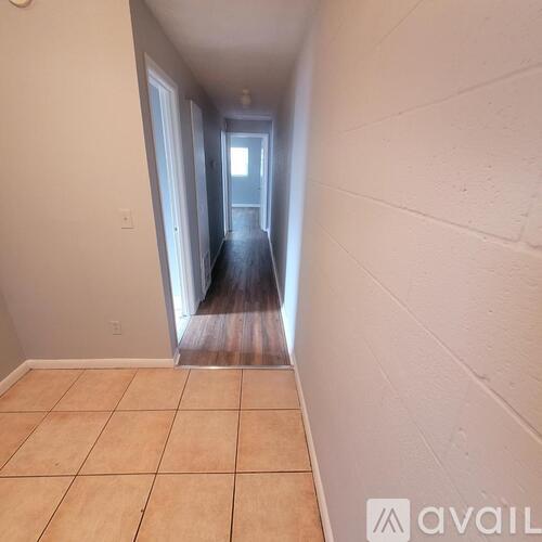 A hallway with a wooden floor and white walls.