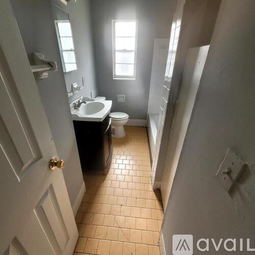A bathroom with a toilet, sink, and a window.