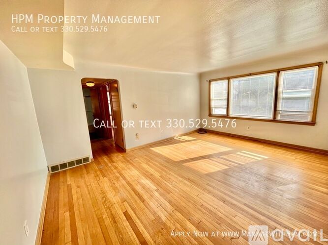 A room with wooden flooring and a door leading to another room.