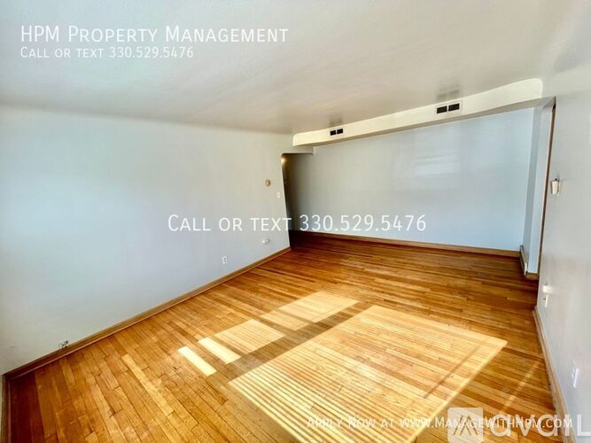 A room with wooden flooring and a white wall with HPM Property Management written on it.