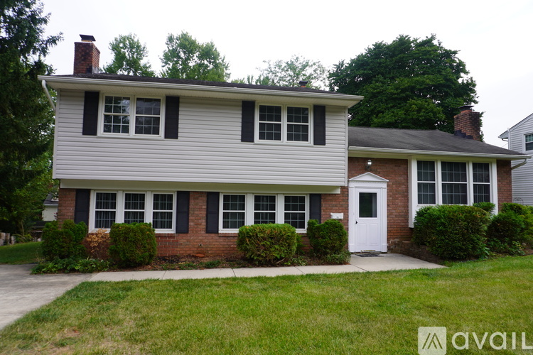 A house with a white door and black shutters is for sale.