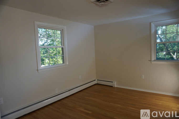 A room with two windows and wooden floors.