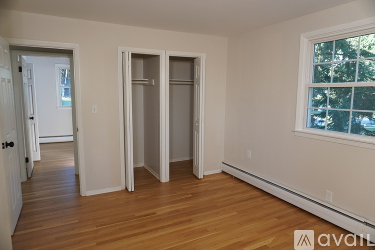 A room with wooden floors and a window showing trees outside.