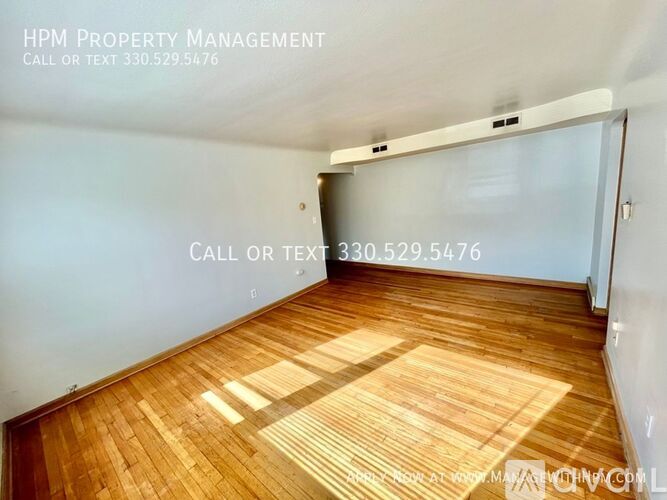 A room with wooden flooring and a white wall with HPM Property Management written on it.