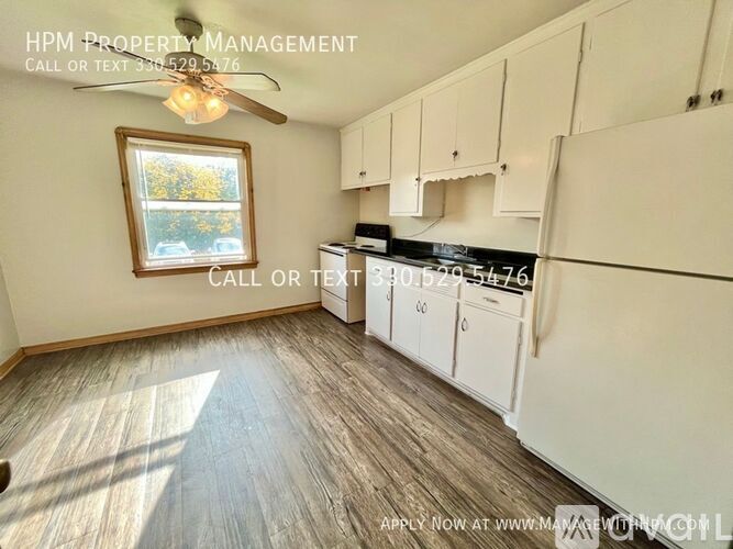 A well-lit kitchen with a window and a fan, and a sign that says "HPM PROPERTY MANAGEMENT".