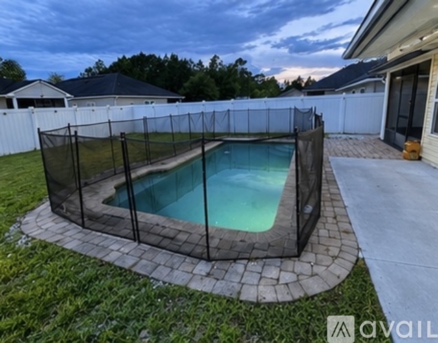 A pool enclosed by a black fence with a white house in the background.
