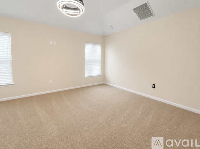 A room with beige carpeting and a ceiling fan.