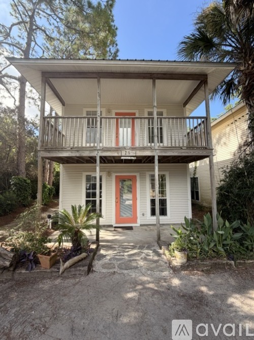 A white house with a red door and a balcony.
