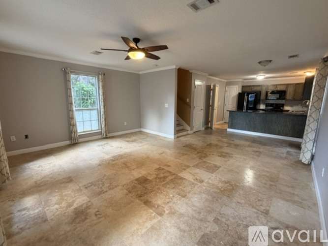 A spacious living room with a ceiling fan and tiled flooring.
