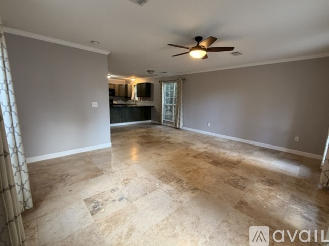 A spacious room with a ceiling fan and a marble floor.
