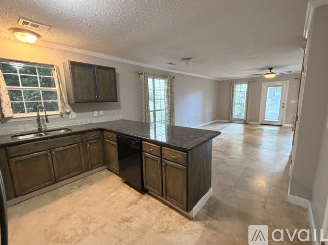 A kitchen with dark wood cabinets and a black dishwasher.