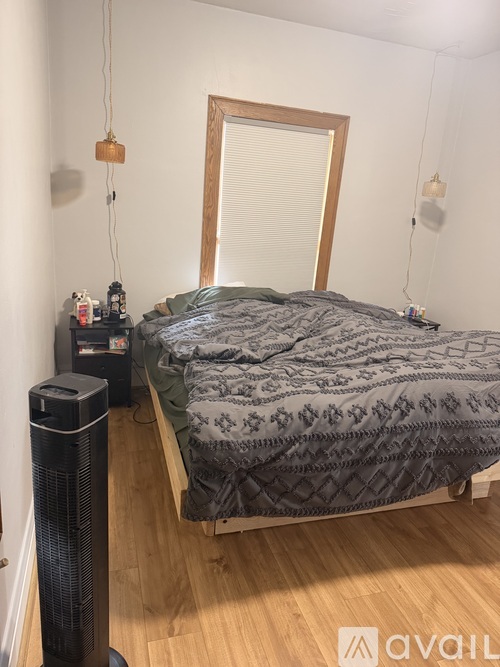 A bedroom with a bed, a fan, and a mirror.