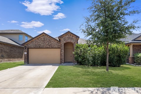 A house with a brown garage door and a tree in front.