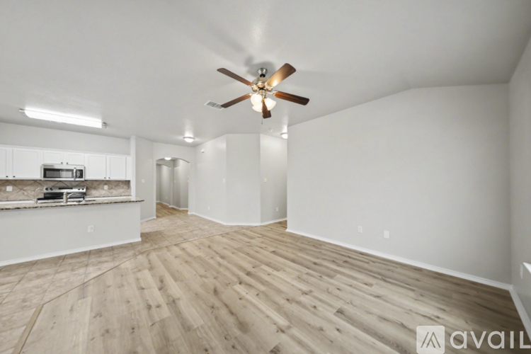 A spacious room with a ceiling fan and wooden flooring.