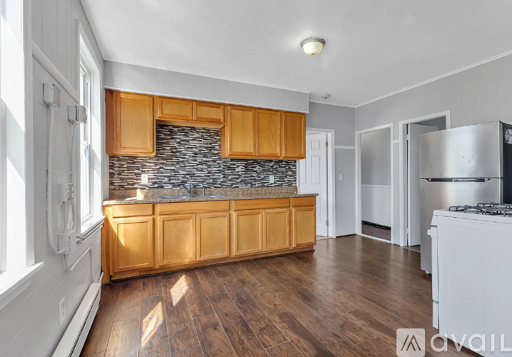 A kitchen with wooden cabinets and a stone backsplash.
