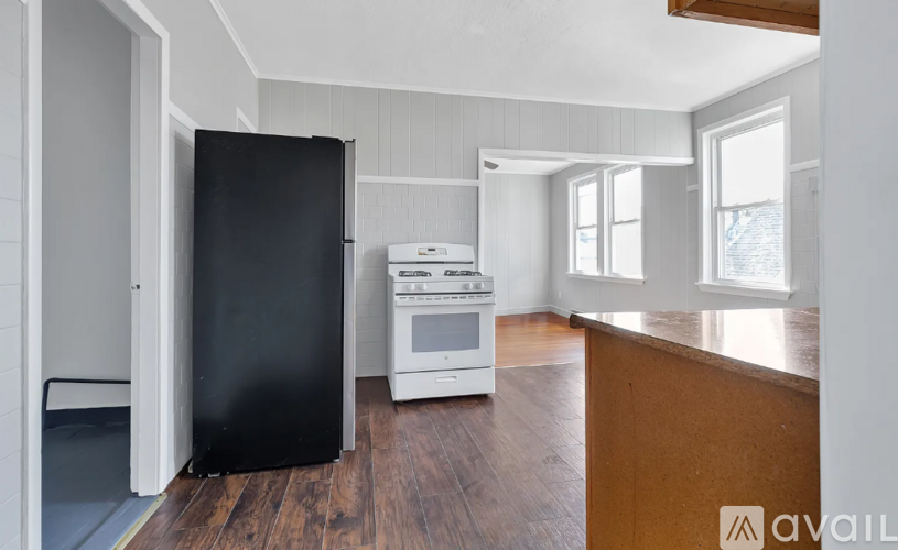 A kitchen with a black refrigerator, white oven, and wooden floors.