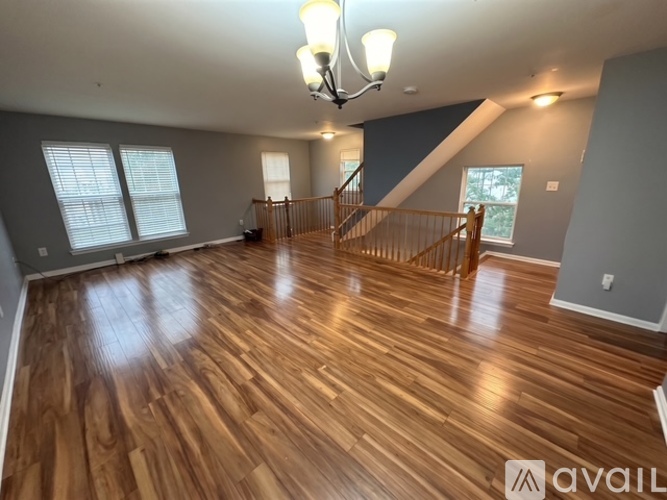 A spacious room with wooden flooring and a staircase.
