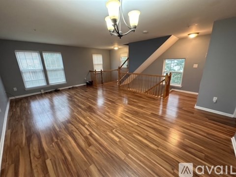 A spacious room with wooden flooring and a staircase.