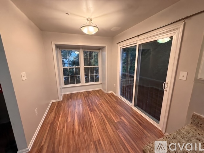 A room with wooden floors and a window with a view of trees.