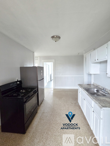 A kitchen with a black stove top oven and white cabinets.